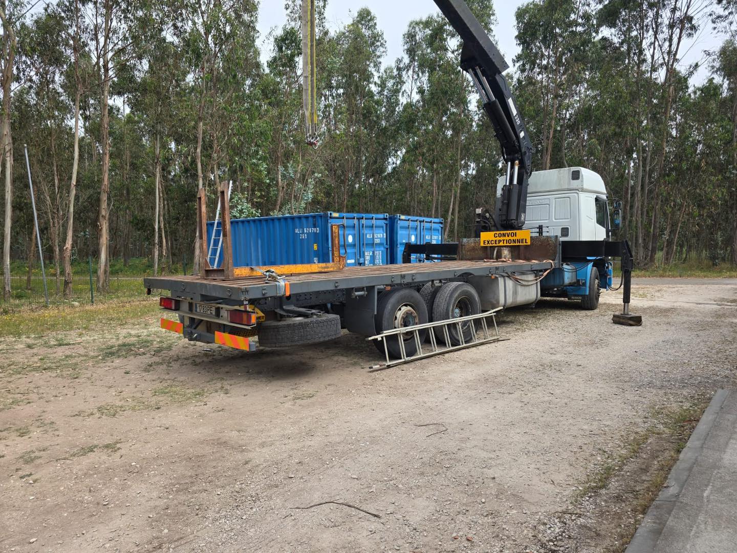 Vrachtwagen met kraan en open oplegger voor het laden en lossen van transportmateriaal